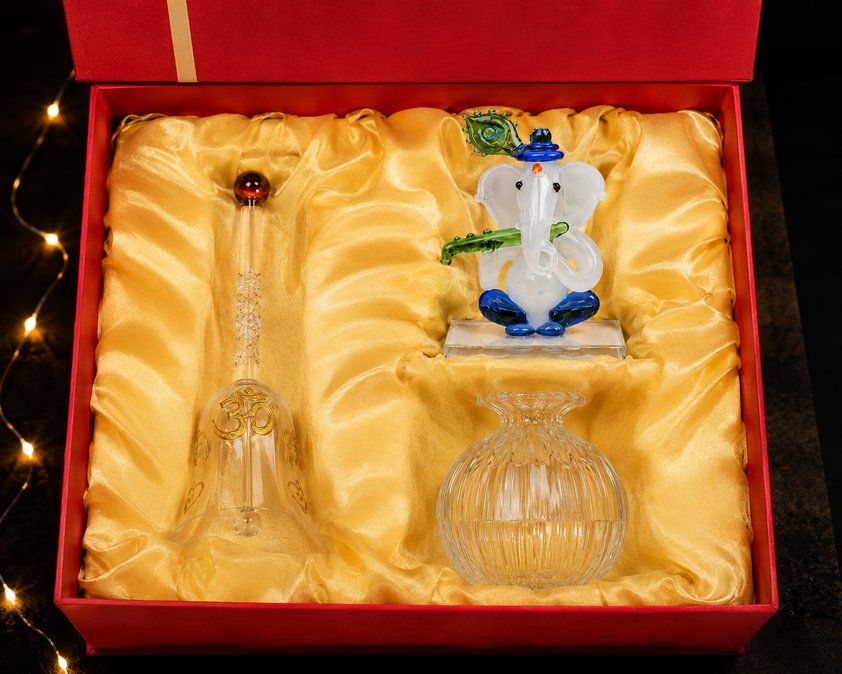 The Divine Trio corporate gift box — glass Ganesha idol, glass bell and modak diya in a red gift box lined with gold silk